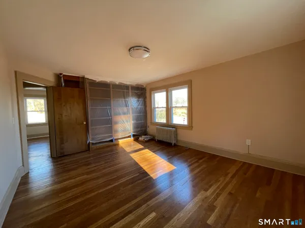 an empty room with wooden floor and windows