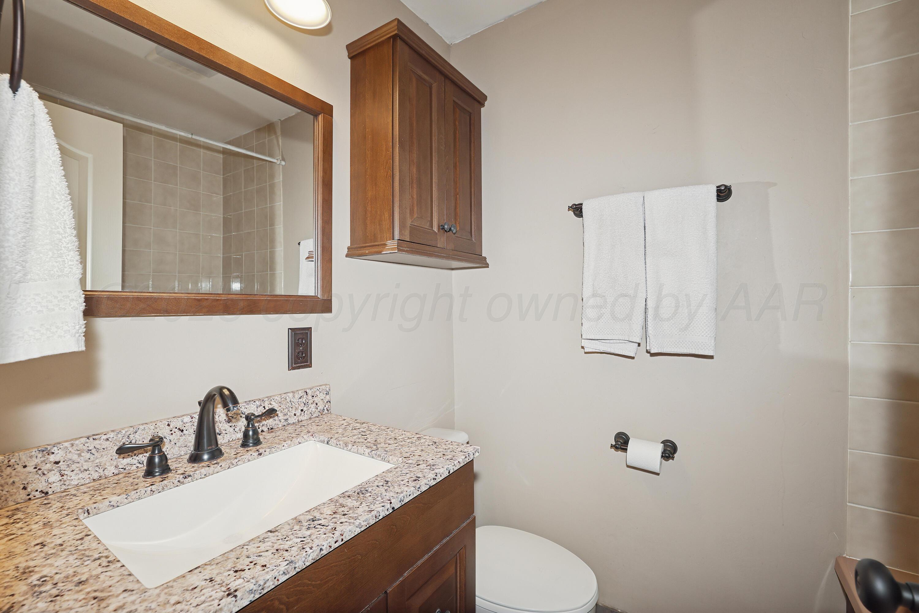 13901 Tangle Aire Point Amarillo, TX 79118 - Photo 20 of 55 a bathroom with a granite countertop sink toilet and mirror