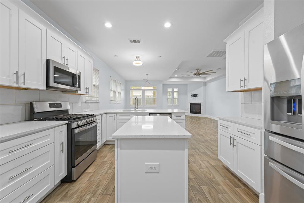 3807 Winding Road Arlington, TX 76016 - Photo 5 of 23 Open-concept kitchen featuring white shaker cabinetry, stainless steel appliances, light countertops, wood-finish flooring, and a central island