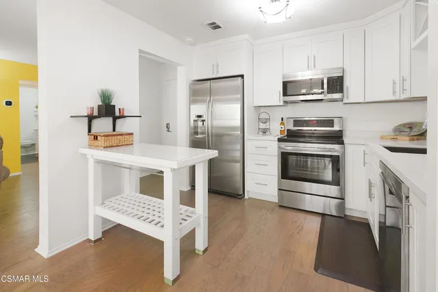 a kitchen with stainless steel appliances kitchen island granite countertop a stove a sink and a refrigerator