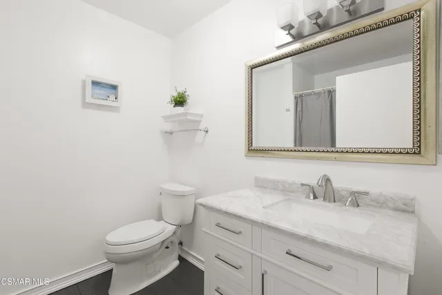 a bathroom with a granite countertop toilet sink and mirror