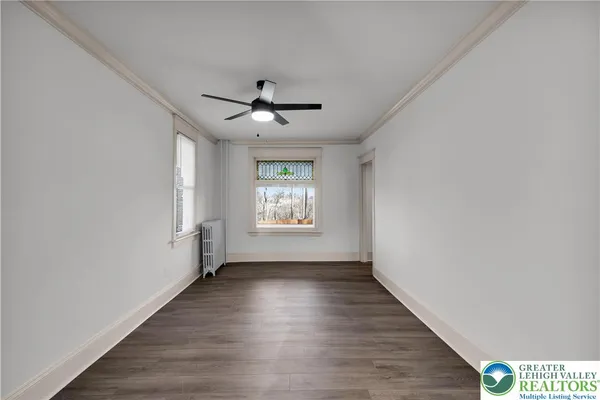 a view of an empty room with a window and wooden floor