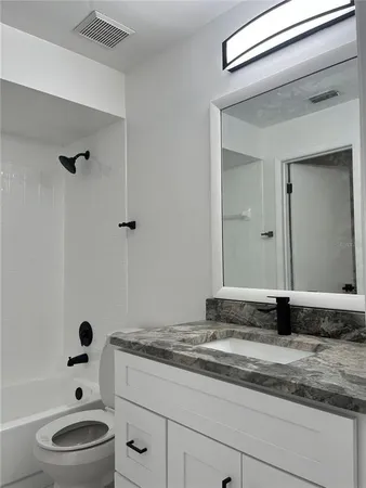 a bathroom with a granite countertop sink a toilet and a mirror