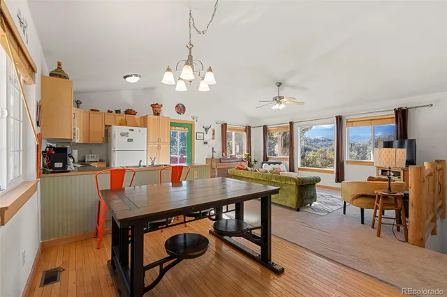 a room with kitchen island a dining table and chairs with wooden floor