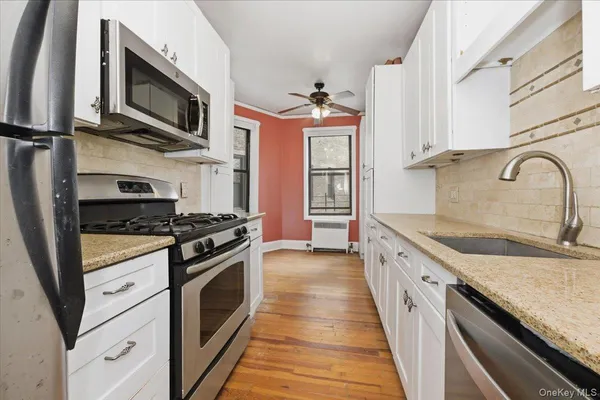 a kitchen with stainless steel appliances granite countertop a stove top oven a sink dishwasher and a microwave oven with cabinets