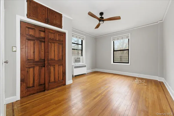an empty room with wooden floor closet and windows