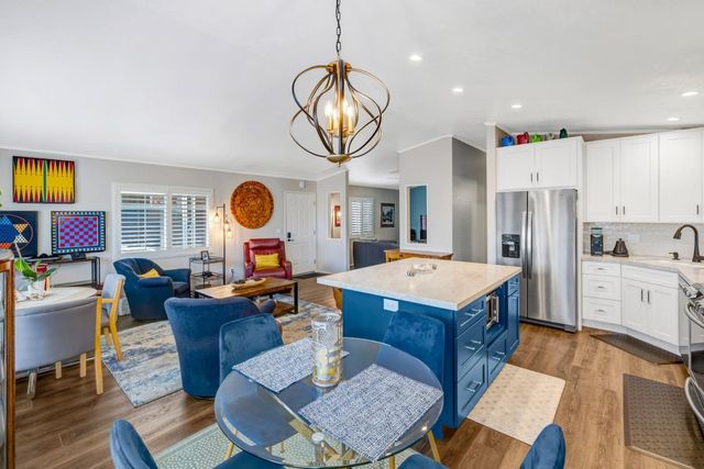 a living room with granite countertop kitchen island stainless steel appliances furniture a rug kitchen view and a sink