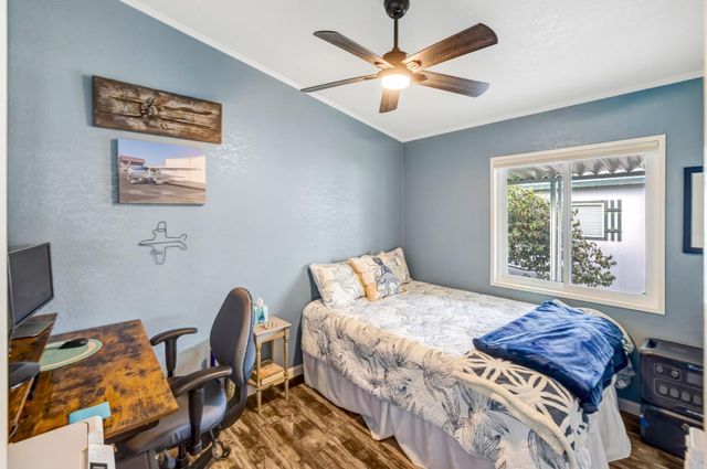 a bedroom with a bed a computer on a desk and chair