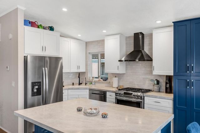 a kitchen with stainless steel appliances a sink a stove a refrigerator and cabinets