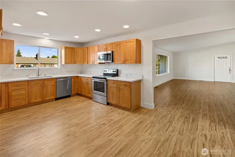 a kitchen with stainless steel appliances granite countertop a sink a stove top oven and wooden floors