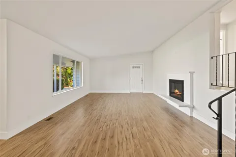a view of empty room with wooden floor and fireplace