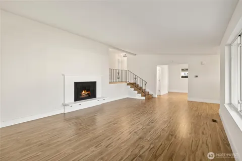 a view of empty room with wooden floor and fireplace