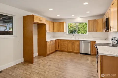 a kitchen with stainless steel appliances granite countertop a refrigerator a sink a stove and white cabinets with wooden floor