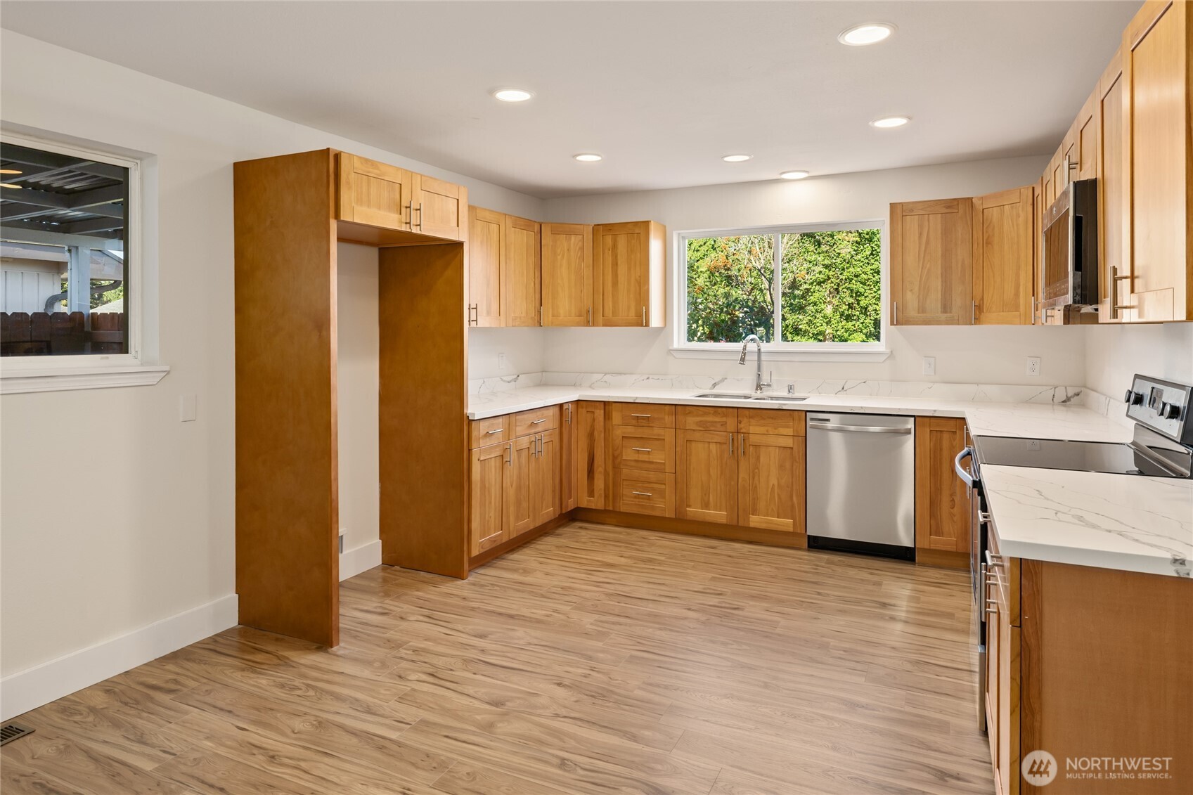 1003 9th Street Northwest Puyallup, WA 98371 - Photo 10 of 40 a kitchen with stainless steel appliances granite countertop a refrigerator a sink a stove and white cabinets with wooden floor