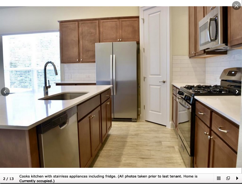 8813 Moccasin Path Austin, TX 78736 - Photo 2 of 10 Kitchen with appliances with stainless steel finishes, a center island with sink, light stone counters, and tasteful backsplash