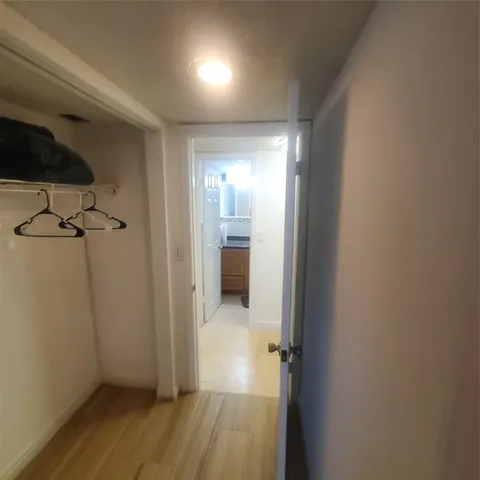 a view of a hallway with wooden floor and a bathroom
