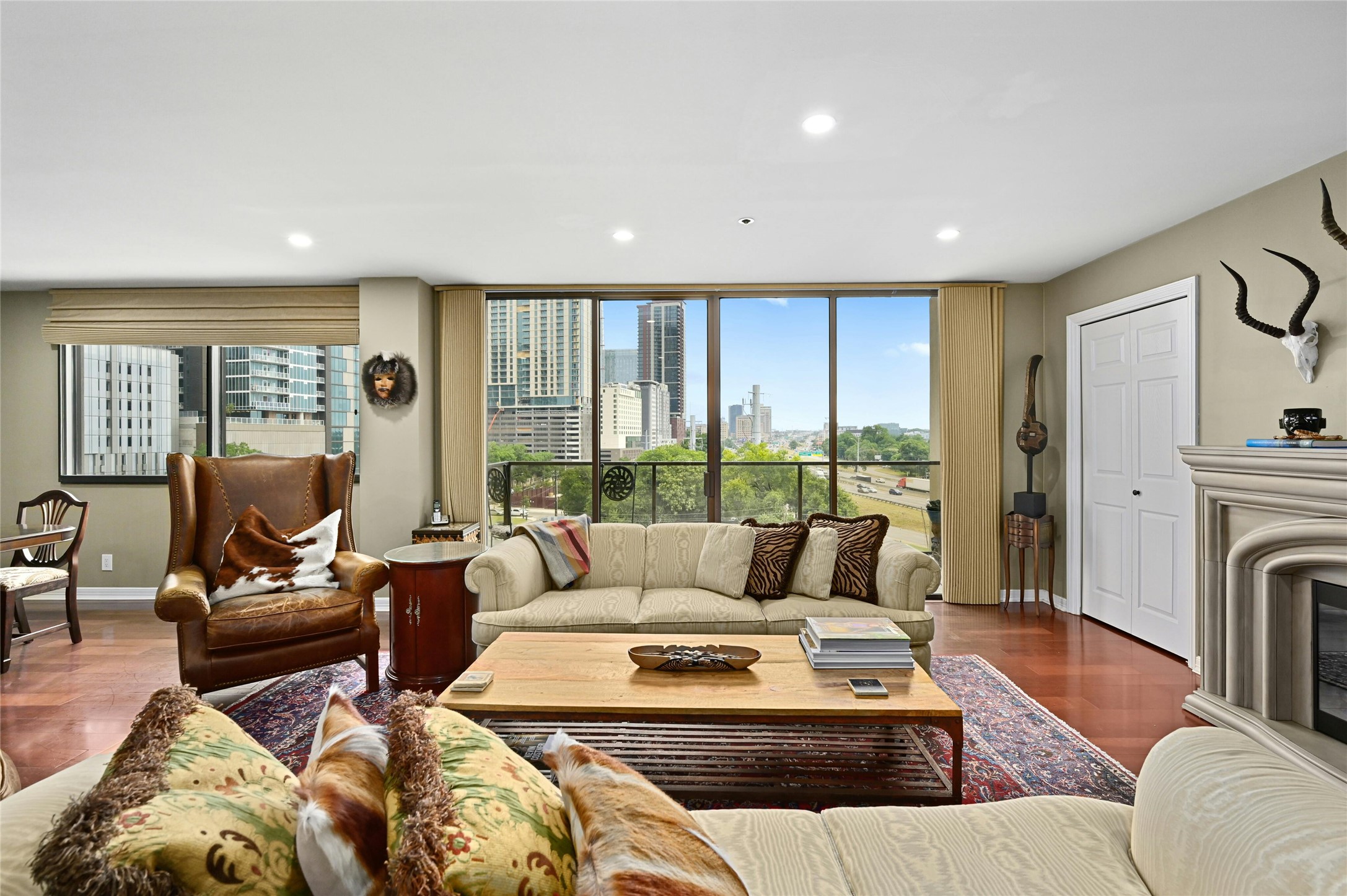 40 North Interstate Highway 35, Unit 8C1 Austin, TX 78701 - Photo 33 of 36 Open floor plan living room with terrace glass door, offering a bright, airy ambiance and elegant wood flooring. Enjoy a scenic view blending cityscape and lush greenery, creating a serene, picturesque setting.