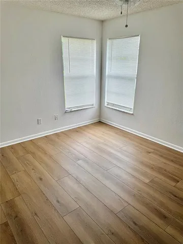 an empty room with wooden floor cabinet and windows