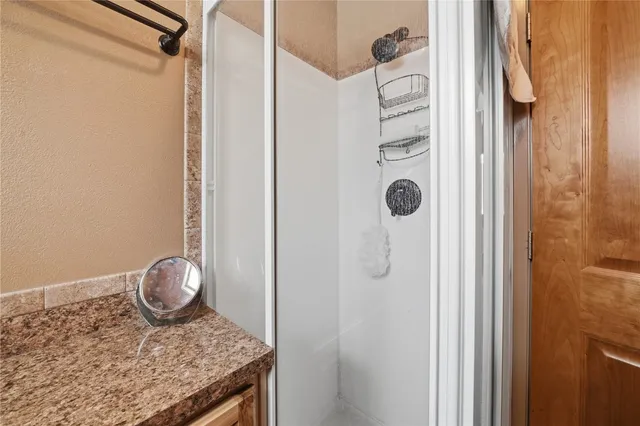 a bathroom with a granite countertop shower and mirror