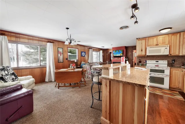 a living room with furniture kitchen area and a large window