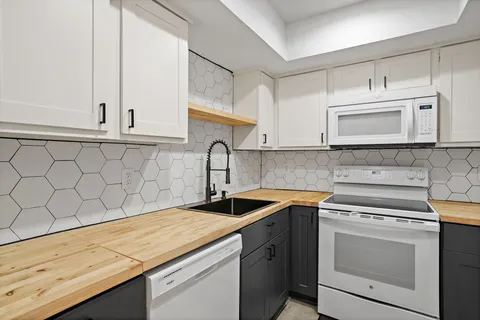 a kitchen with granite countertop white cabinets and a stove with wooden floor