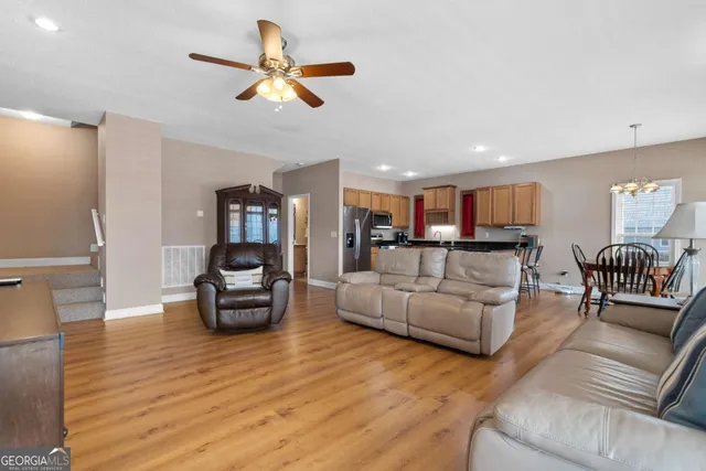 a living room with furniture kitchen view and a wooden floor