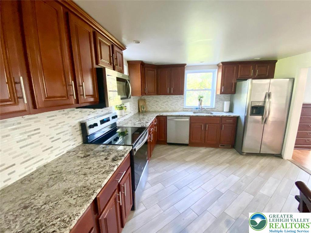 244 Learn Road Tannersville, PA 18372 - Photo 29 of 69 a kitchen with granite countertop a refrigerator a stove top oven a sink and dishwasher