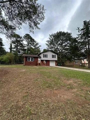 a front view of a house with a yard and trees