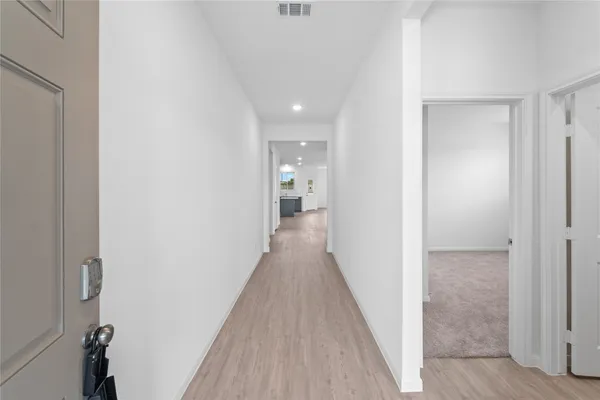 a view of a hallway with wooden floor and a bathroom