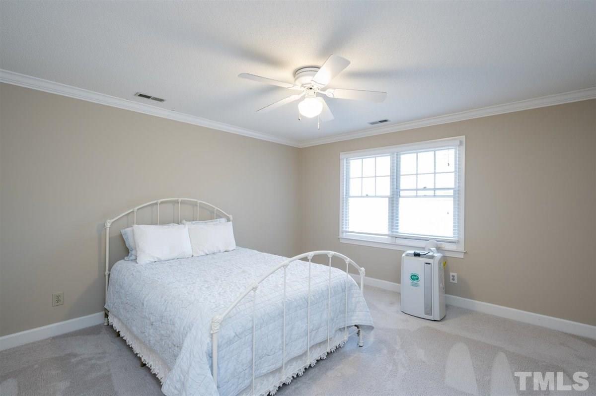 7921 Footman Way Raleigh, NC 27615 - Photo 20 of 28 a bedroom with a bed and a chandelier