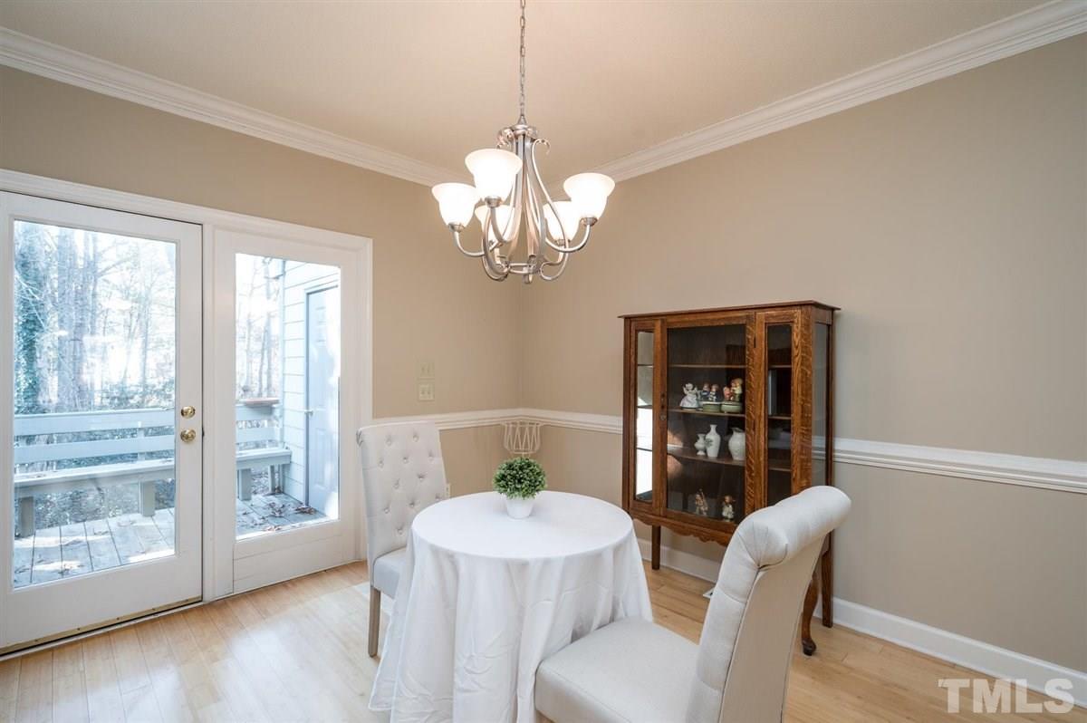 7921 Footman Way Raleigh, NC 27615 - Photo 8 of 28 a dining room with wooden floor a chandelier a wooden table and chairs