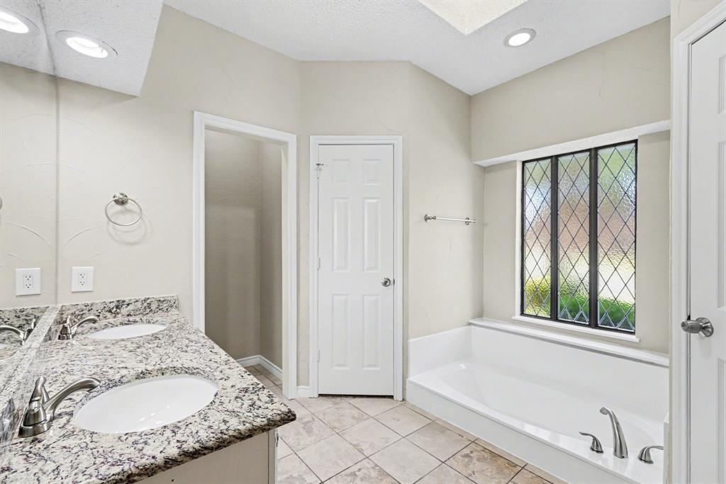 505 Springhill Drive Hurst, TX 76054 - Photo 16 of 25 a en suite bathroom with a granite countertop tub and a sink