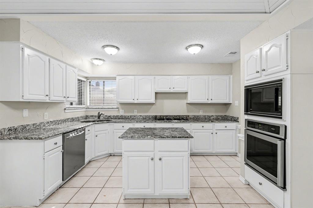 505 Springhill Drive Hurst, TX 76054 - Photo 7 of 25 a kitchen with granite countertop white cabinets stainless steel appliances and a sink