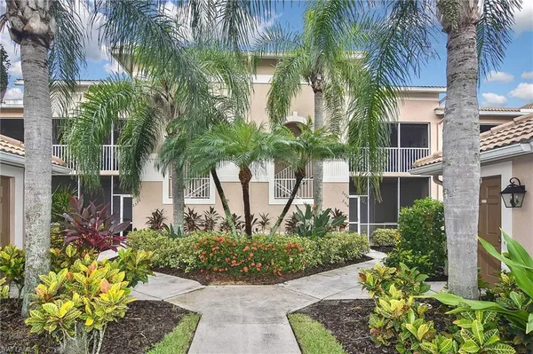 a front view of a multi story residential apartment building with yard and green space