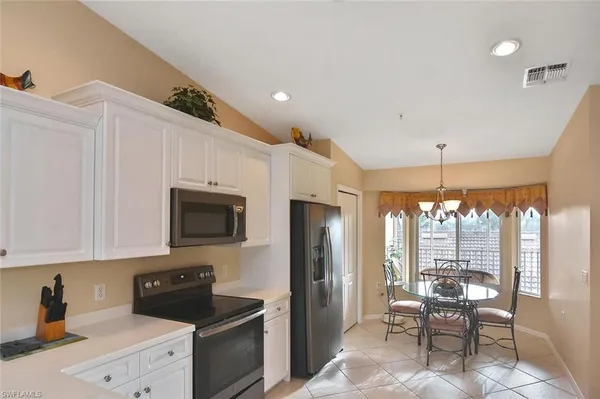 a kitchen with stainless steel appliances granite countertop a stove top oven a sink dishwasher a dining table and chairs with wooden floor