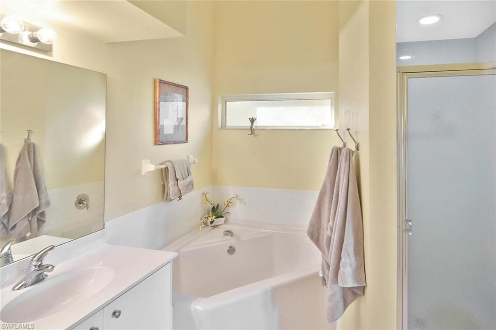 3870 Sawgrass Way, Unit 2521 Naples, FL 34112 - Photo 36 of 46 a bathroom with a tub sink and mirror