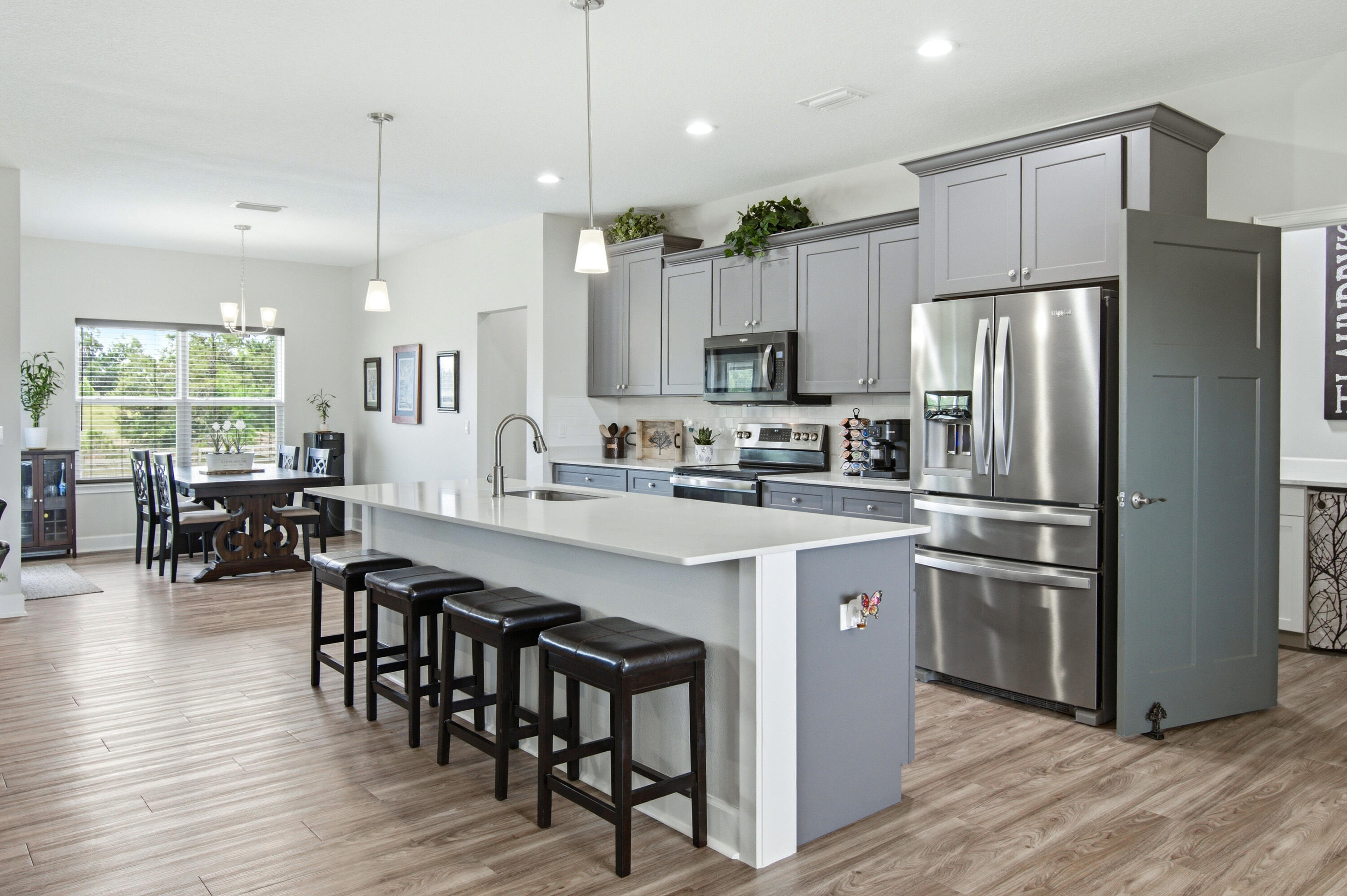 10172 98th Street, Unit 2 Live Oak, FL 32060 - Photo 3 of 37 a kitchen with stainless steel appliances granite countertop a refrigerator a stove a sink a dining table and chairs with wooden floor