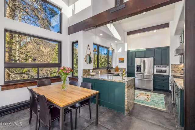 a kitchen with stainless steel appliances a dining table chairs and refrigerator