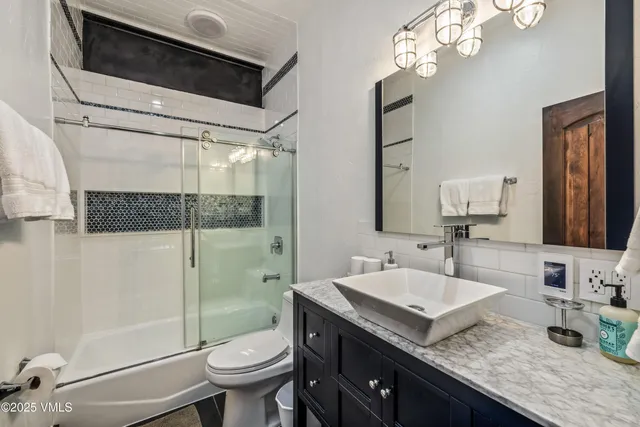 a bathroom with a granite countertop sink a toilet a mirror and shower