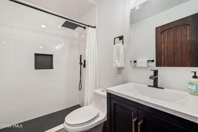 a bathroom with a sink a toilet a mirror and shower