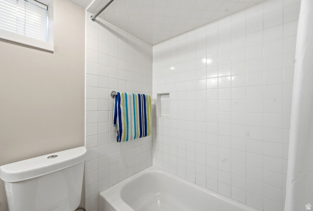 310 East 600 South Centerville, UT 84014 - Photo 21 of 41 Bathroom featuring a white subway tile shower surround with an integrated niche, a white tub, and a white toilet