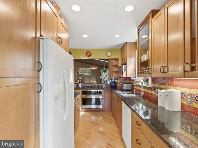 a kitchen with stainless steel appliances granite countertop a sink a stove and a refrigerator