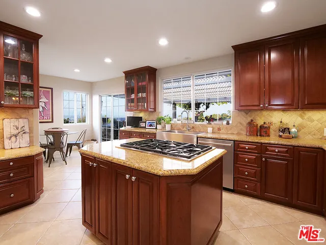 a kitchen with stainless steel appliances granite countertop a stove a sink dishwasher and a refrigerator with wooden cabinets