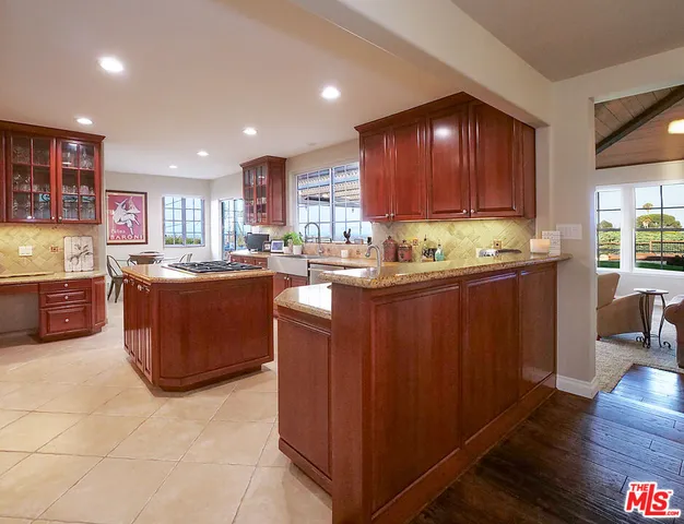a kitchen with kitchen island granite countertop a sink counter top space appliances and cabinets