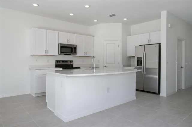 a kitchen with stainless steel appliances white cabinets a sink a stove a microwave and a refrigerator