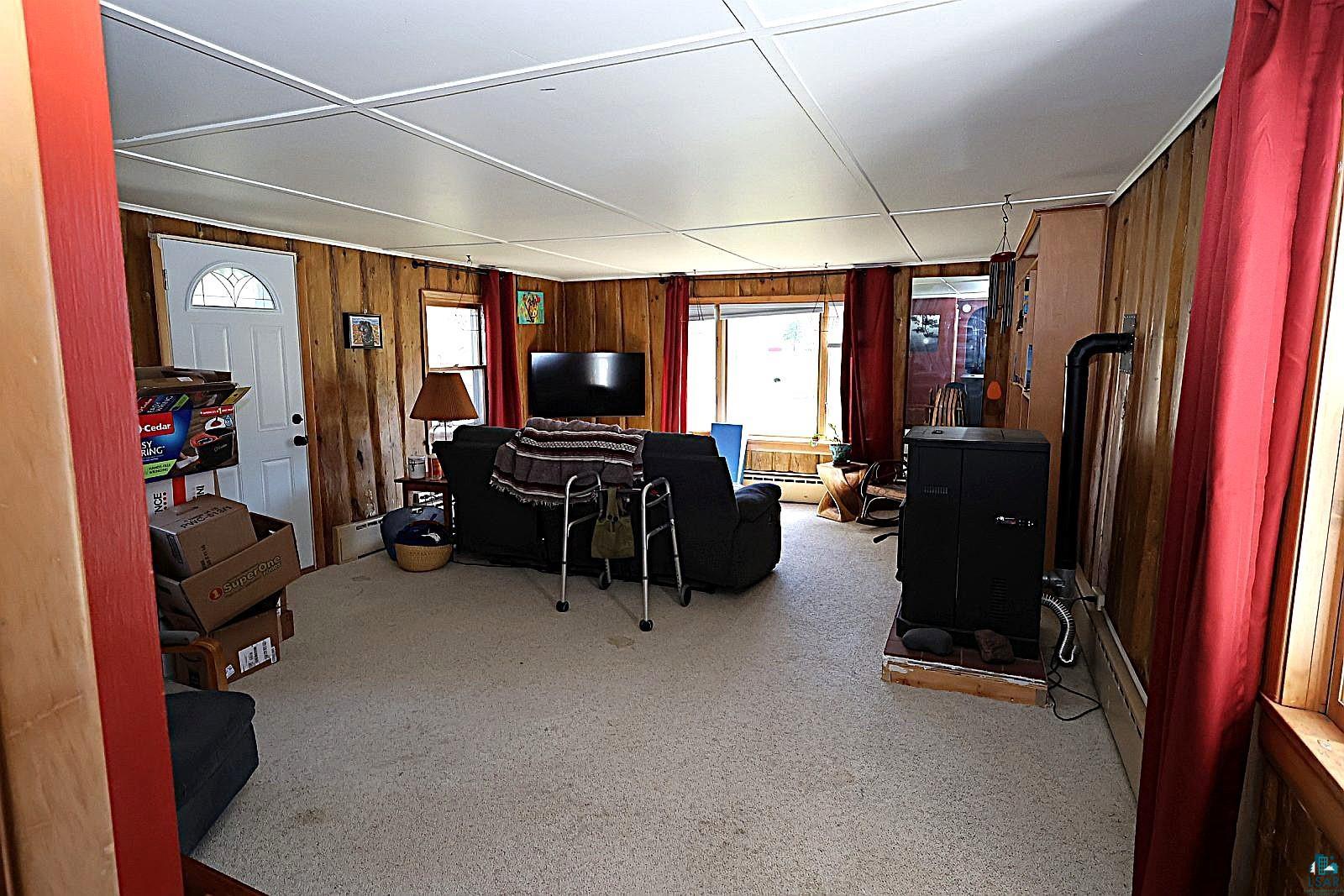 83185 Washington Avenue Port Wing, WI 54865 - Photo 12 of 26 Wood-paneled room featuring a black wood-burning stove on a raised hearth