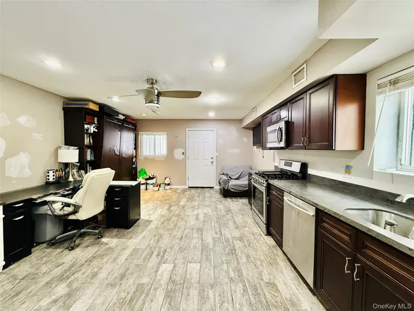 a kitchen with stainless steel appliances kitchen island granite countertop a stove top oven a sink dishwasher a dining table and chairs with wooden floor