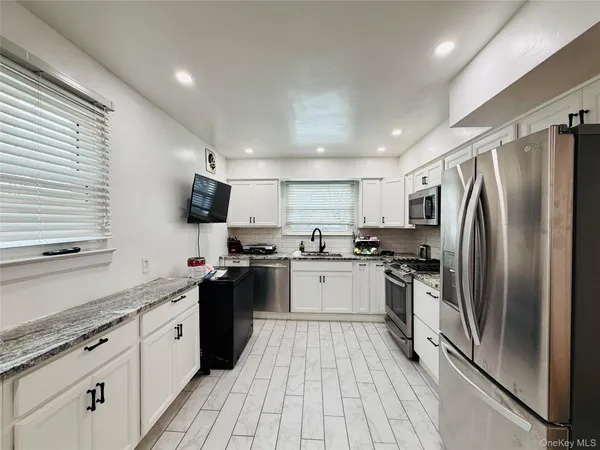 a kitchen with stainless steel appliances granite countertop a stove a sink dishwasher and a microwave oven with white cabinets