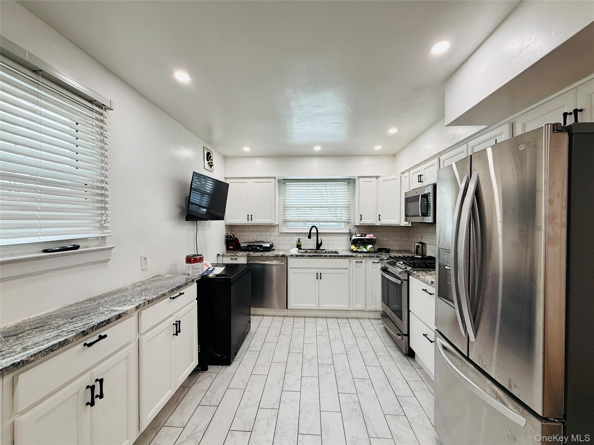 1663 Waring Avenue Bronx, NY 10469 - Photo 7 of 34 a large kitchen with stainless steel appliances granite countertop a refrigerator a sink dishwasher a stove and white cabinets with wooden floor