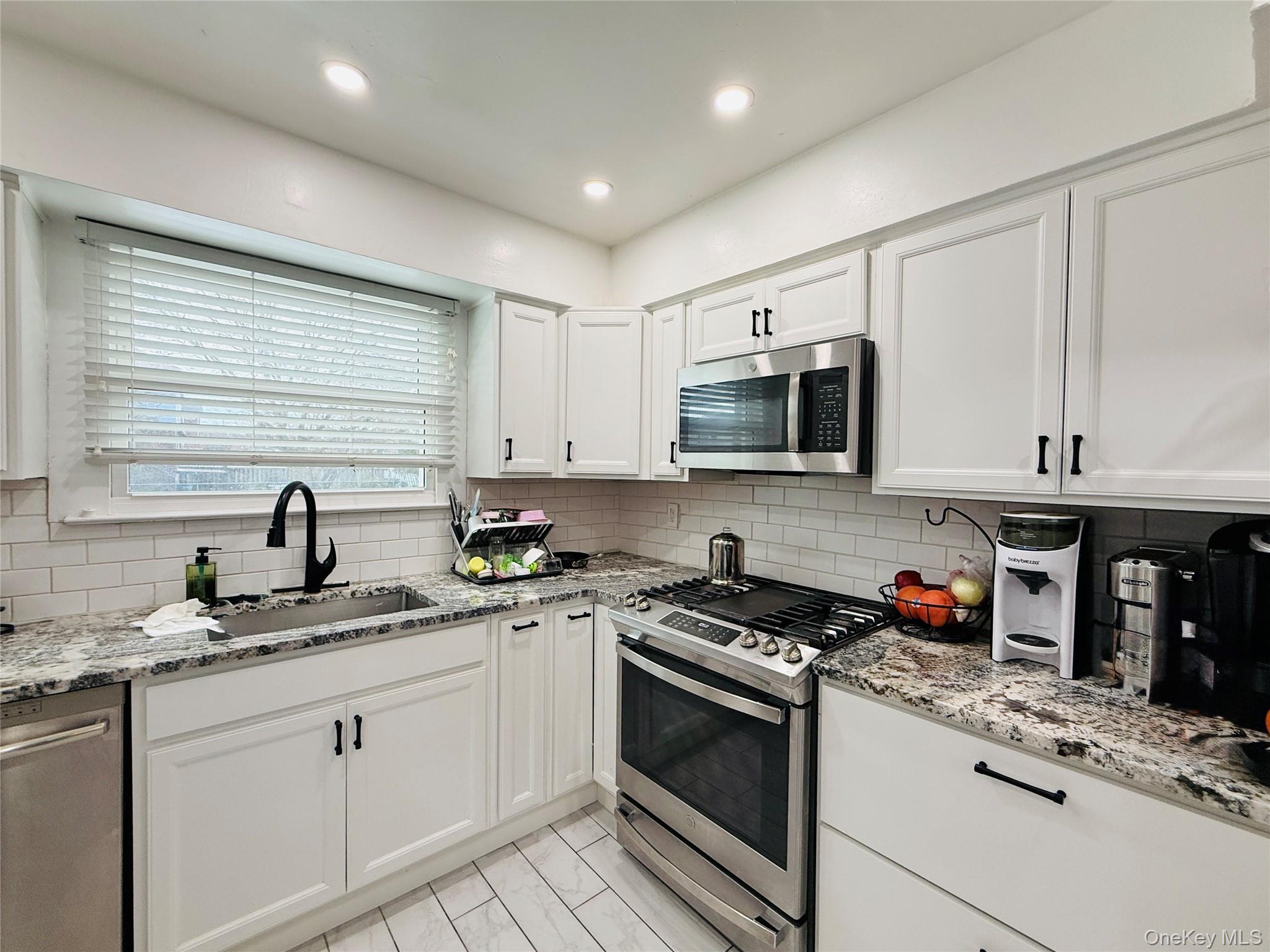 1663 Waring Avenue Bronx, NY 10469 - Photo 8 of 34 a kitchen with stainless steel appliances granite countertop a stove a sink dishwasher and a microwave oven with white cabinets